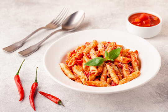 Classic italian pasta penne alla arrabiata with fresh basil on a light background