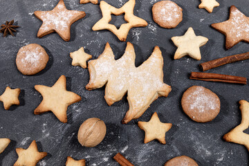Arrangement of homemade Christmas cookies, cinnamon, walnuts, anise stars on black close up.