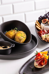 Dinner with grilled potato and assorted cheese, prosciutto and fruits, bruschetta on a plate