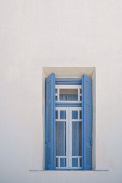 Blue wooden window against white wall backgrounds of traditional Greek Island buildings