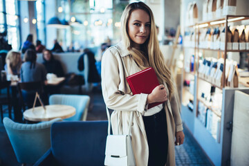 Smiling young woman with book in modern cafe