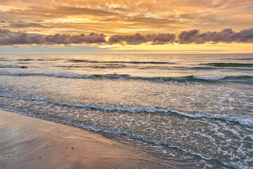 Sunset on Baltic Sea white bright golden orange color and rough sea

