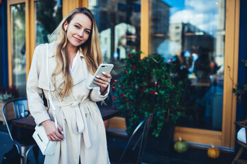 Fototapeta premium Happy woman using smartphone in cafe looking at camera
