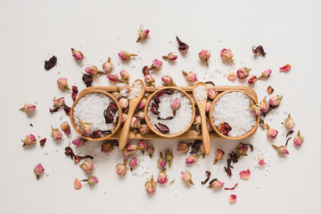 Wooden bowls filled with white bath sea salt with dry rose buds. Beauty treatment for spa and...