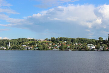 The city of Ples on the banks of the Volga River - view from the ship. green hills, houses, a church with domes and a bell tower.