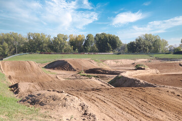 Track for motocross racing competition with breaking bumps under a blue cloudy sky on a sunny day