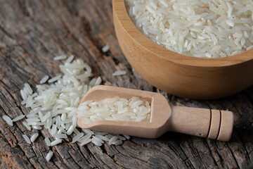 Pile of white rice in a wooden spoon, on a wooden background.