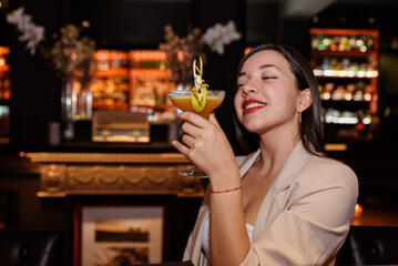 happy young woman drinks a cocktail at a bar counter