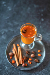 Sea buckthorn tea in a glass on a dark background.