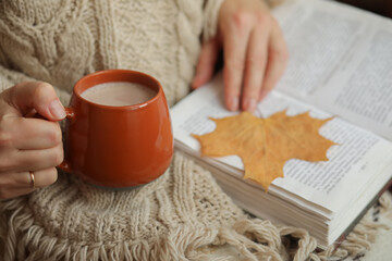 person holding cup of tea and reading a book