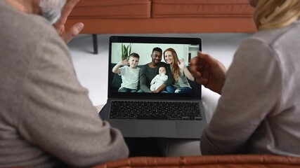 Middle-aged couple using laptop computer for video connection with a grown daughter and her multiracial family, grey-haired man and woman talking online with mixed-race family on computer screen - Powered by Adobe