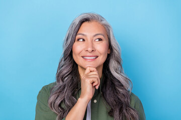 Photo of confident dreamy lady pensioner dressed green shirt thinking arm chin looking empty space isolated blue color background