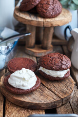 Ice Cream Sandwices: Vanilla ice cream sandwiched between two chocolate cookies on a wooden board on a wooden background.