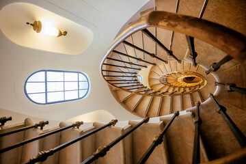 Old spiral staircase in interior of historical house. Old architecture with stairs, window and space between floors