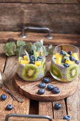 Chia pudding with kiwi, blueberry, mango and sage. Side view, wooden background.