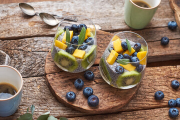 Chia pudding with kiwi, blueberry, mango and sage. Side view, wooden background.