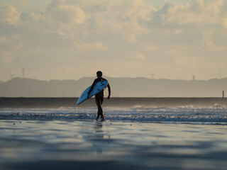 surfer on the beach at sunset