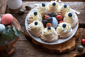 Easter Pavlova cake. Blue, pink eggs, decor, coffee, side view, blueberry.