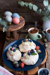 Easter Pavlova cake. Blue, pink eggs, decor, coffee, side view, blueberry.