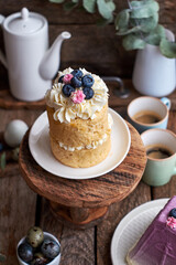 Easter cake with cream, blueberries.  Flowers, blueberry, eggs. Wooden background, side view	