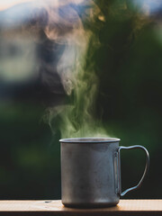 A cup of coffee with smoke with sunrise landscapes background. Morning coffee cup