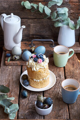 Easter cake with cream, blueberries.  Flowers, blueberry, eggs. Wooden background, side view	