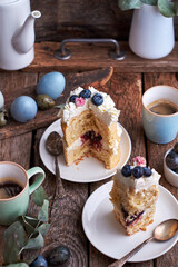 Easter cake with cream, blueberries.  Flowers, blueberry, eggs. Wooden background, side view	