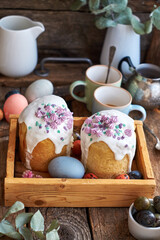 Traditional Easter cake with glaze and decorated mini meringue. Wooden background, side view, pink, blue, green, eggs, eucalyptus