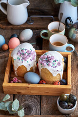 Traditional Easter cake with glaze and decorated mini meringue. Wooden background, side view, pink, blue, green, eggs, eucalyptus