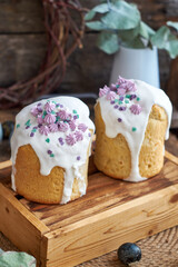 Traditional Easter cake with glaze and decorated mini meringue. Wooden background, side view, pink, blue, green, eggs, eucalyptus