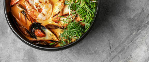 Mediterranean seafood soup with mussels and prawns. Thai tom yum soup on grey clay background.