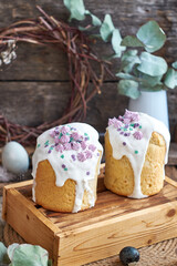 Obraz na płótnie Canvas Traditional Easter cake with glaze and decorated mini meringue. Wooden background, side view, pink, blue, green, eggs, eucalyptus