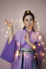 Caucasian woman posing in lilac traditional Chinese hanfu dress holding glowing lights. Concept - interest in Chinese culture, mutual enrichment of cultures, Chinese New Year