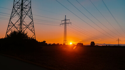 Beautiful sunset view with a dramatic sky and overland high voltage lines near Tabertshausen, Bavaria, Germany