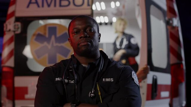 African american paramedic posing with ambulance on background