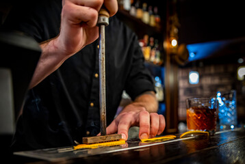 bartender stamping orange peel on the bar counter