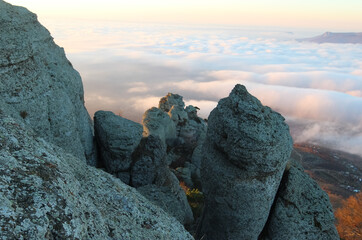 Aerial view of sunrise in the mountains. Clouds with pink reflexes from the sun. Rocks in shadow in foreground