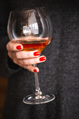 Woman with red manicure holding a wine glass