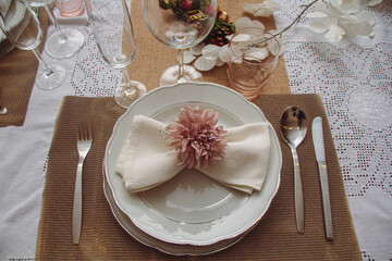 Napkin on dish with fork, knife, spoon, glass and two different cups on shiny tablecloth in Christmas season. Christmas decoration for dining tables