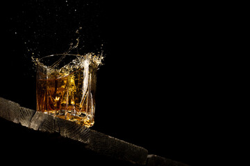 whiskey in a glass on a black background on a wooden table