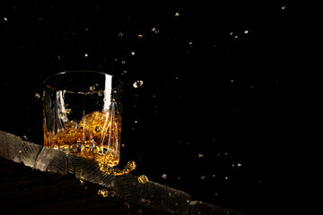 whiskey in a glass on a black background on a wooden table
