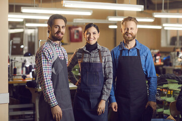 Portrait of three Caucasian experienced smiling shoe and garment factory workers at work. Two men...