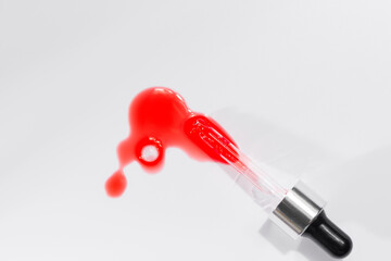 Vertical shot of a small tube and face oil on a pink surface