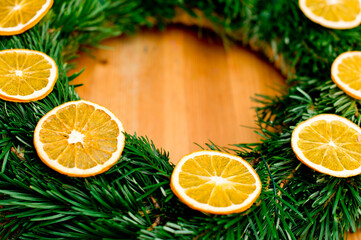 Fototapeta na wymiar Christmas wreath of fir branches decorated with dried orange slices. Advent ornaments.