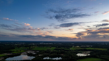 Aerial view of an evening sky over the fields overcast with thunder storm clouds coming in on the sunrise or sunset, taken with drone. High quality photo