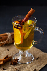 mulled wine and spices.Christmas hot white mulled wine in glass with orange, honey, cinnamon sticks and star anise with spices and ingredients on black background. Spicy warm beverage. copy space