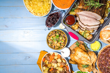Thanksgiving dinner table with new traditional thanksgiving food - chicken, mashed sweet potatoes, green beans, pecan pie, baked ham pork, mac and cheese, stuffing, modern hard sunny light flatlay