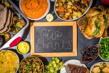 Thanksgiving dinner table with new traditional thanksgiving food - chicken, mashed sweet potatoes, green beans, pecan pie, baked ham pork, mac and cheese, stuffing, modern hard sunny light flatlay