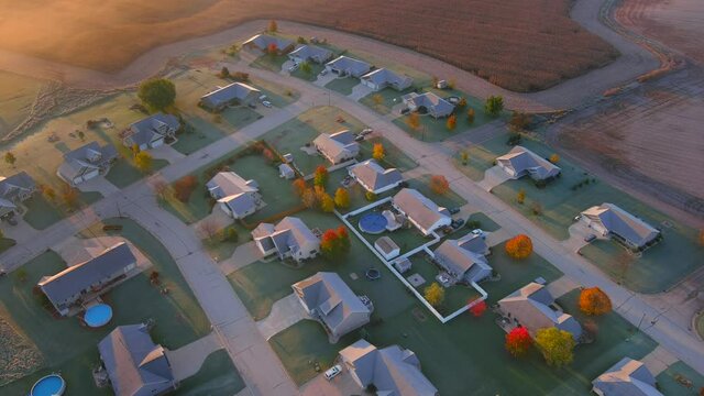 Beautiful frosty Fall neighborhood at dawn, with colorful trees and a little fog, aerial view.
