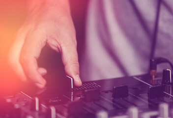 Hands of dj playing music on party in night club. Disc jockey hand on crossfader on sound mixer